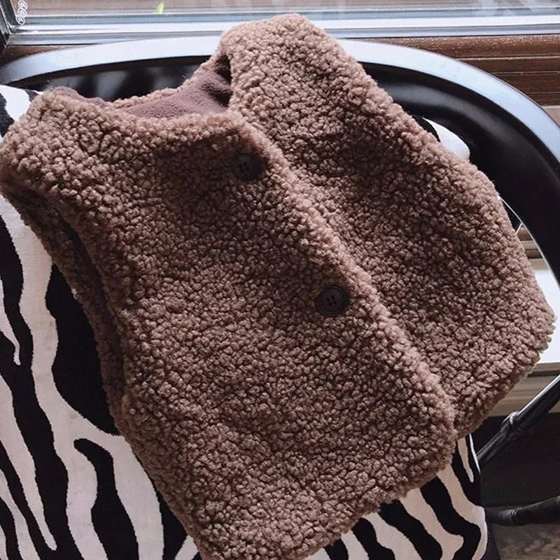 A brown, fuzzy lamb wool vest is displayed on a black and white patterned surface.