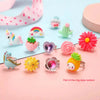 A collection of sparkling gemstone rings and jewelry pieces in various colors and shapes arranged on a pink background.