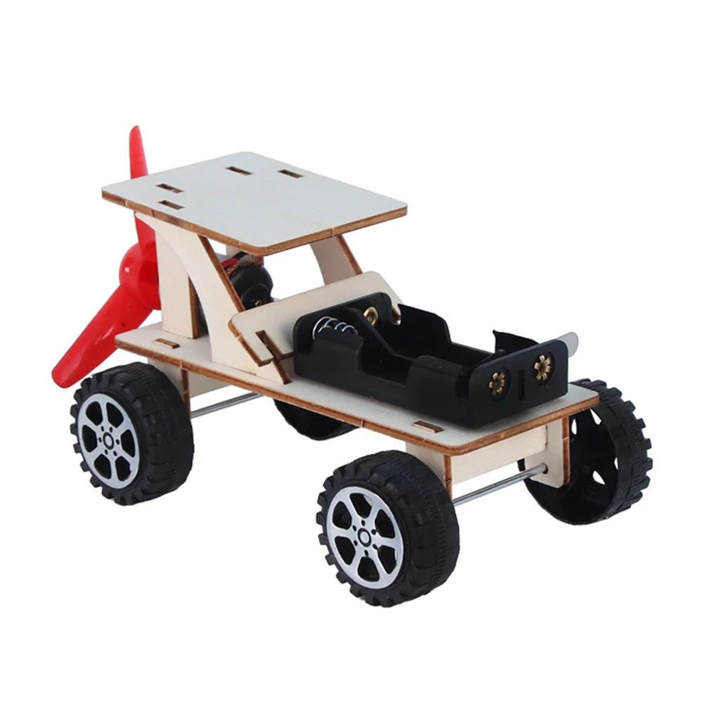 A wooden paddle boat kit with a red paddle and black wheels for a DIY science project.