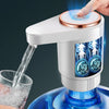 A hand is dispensing water from a white electric dispenser pump into a glass, showing the dual outlet mechanism.