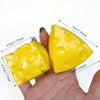 A yellow, squishy cheese ball stress relief squeeze toy is held in a hand, showing its size and texture.