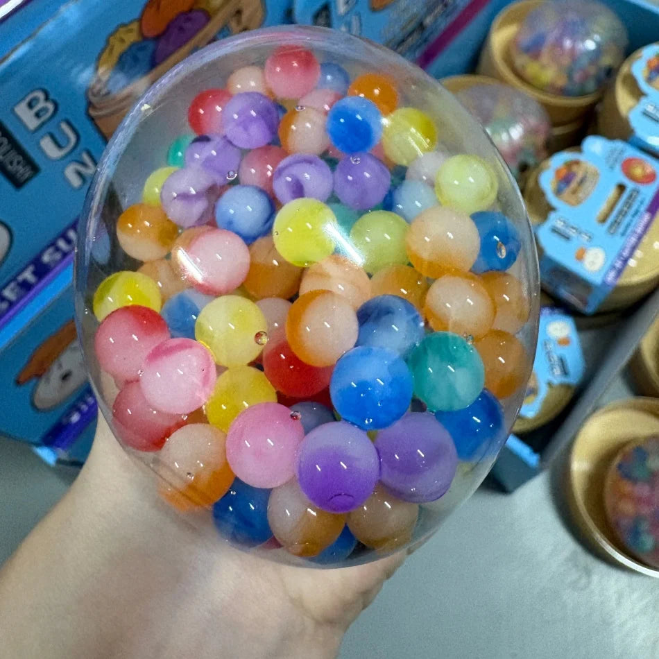 Un bol en verre transparent rempli de perles arc-en-ciel colorées utilisé comme jouet anti-stress