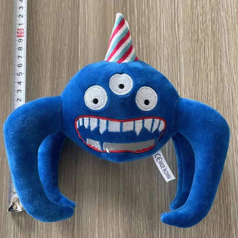 Blaues Plüschtier, das wie ein Monster mit großen Augen und scharfen Zähnen aussieht, mit gestreiftem konischem Hut.