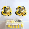 A set of black and gold confetti balloons decorated with graduation text, displayed on a white table.