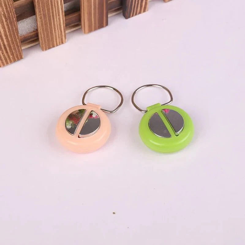 Two plastic hand buzzers, one pink and one green, with metal rings, resting on a white surface.