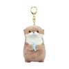 A soft brown plush otter charm with a light gray snout and a blue fish, attached to a gold-colored keyring.