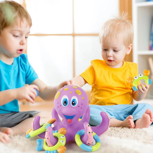 Two toddlers interact with a purple octopus bath toy and related plastic toys.