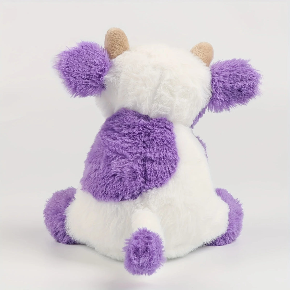 A white and purple plush cow toy with soft fur and small horns.