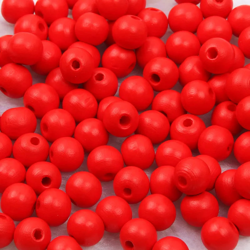 A pile of small, round, natural wooden beads in bright red color.