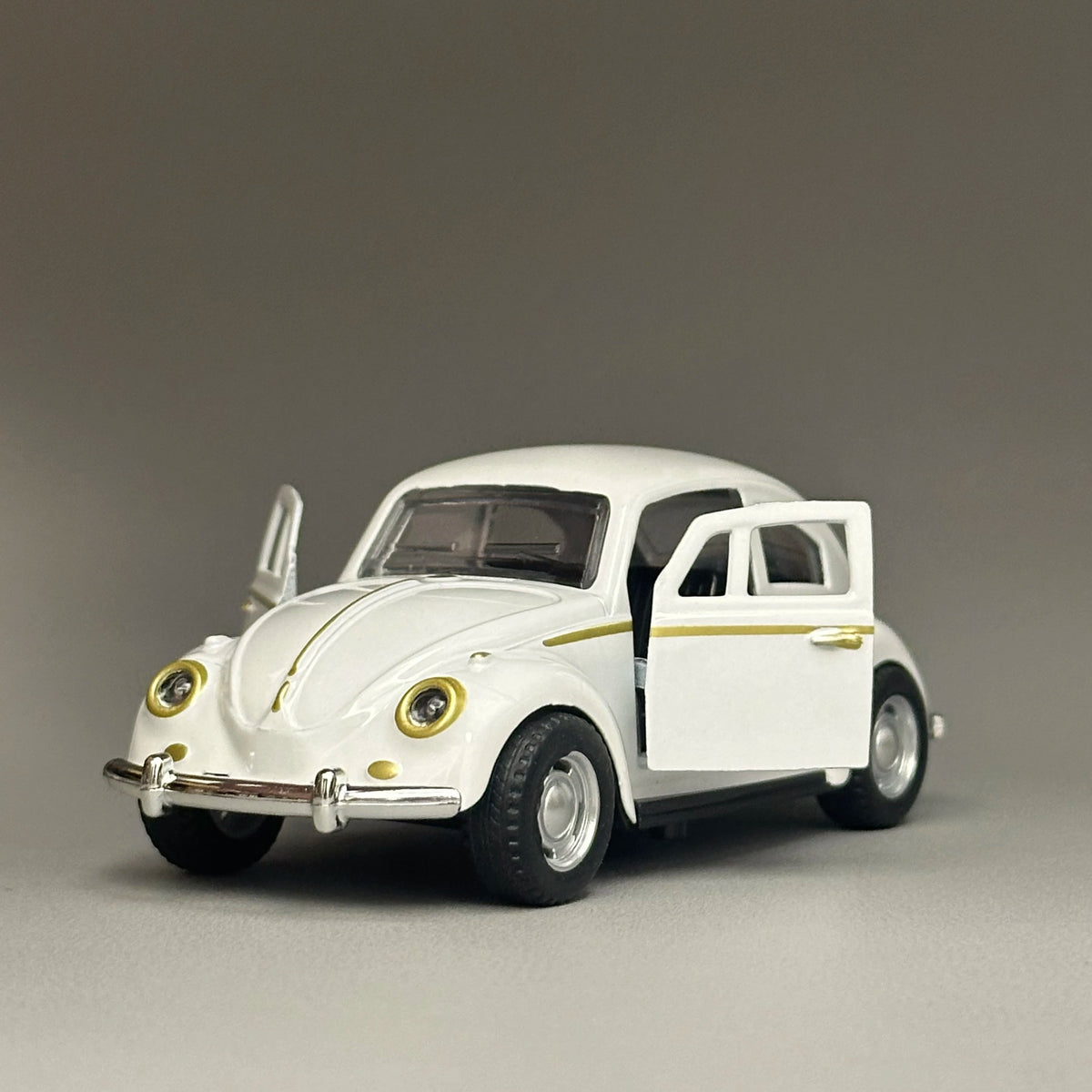 A white diecast model of a classic retro Beetle with gold accents, shown in profile.