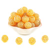 A pile of small, round, golden-yellow rhinestone resin bayberry beads for jewelry making.