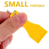 A hand holds a yellow plastic lottery scratcher tool with a metal keychain attached.