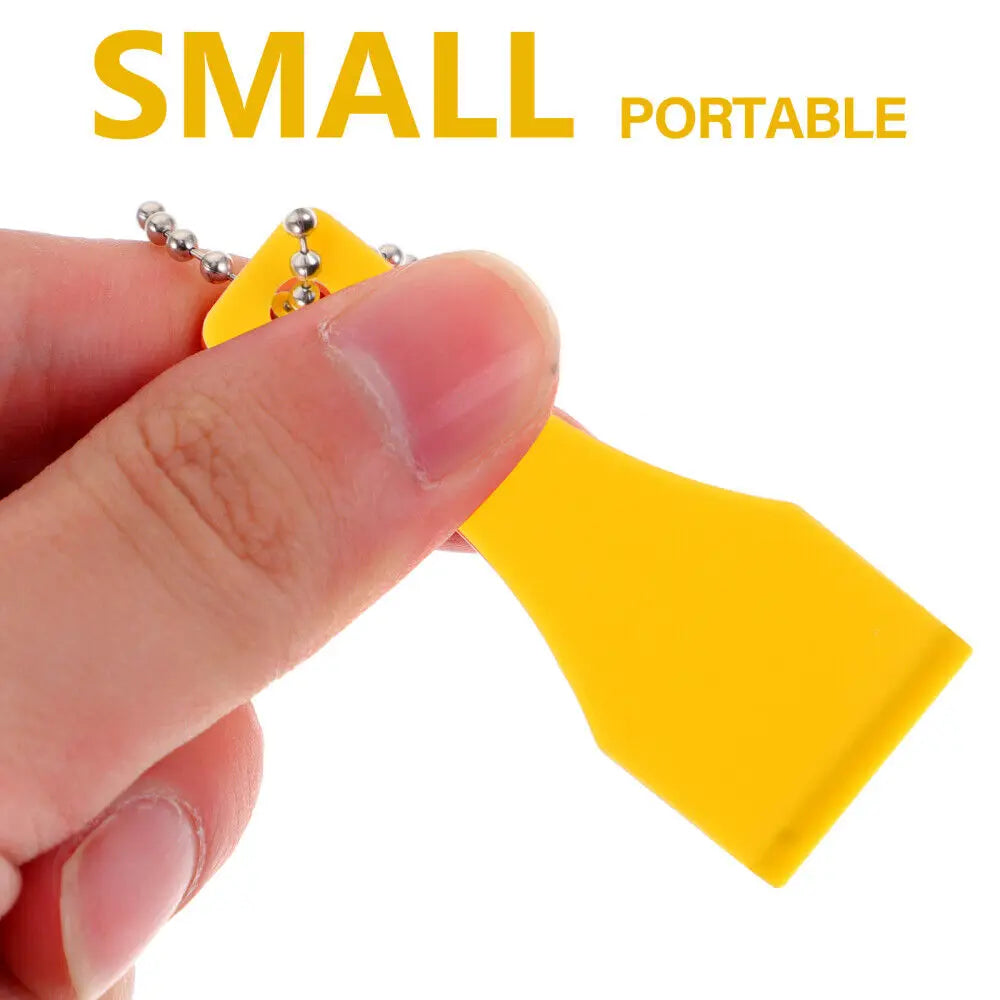 A hand holds a yellow plastic lottery scratcher tool with a metal keychain attached.