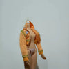 A fashion doll wearing an orange knitted sweater and matching bottoms with a number detail.