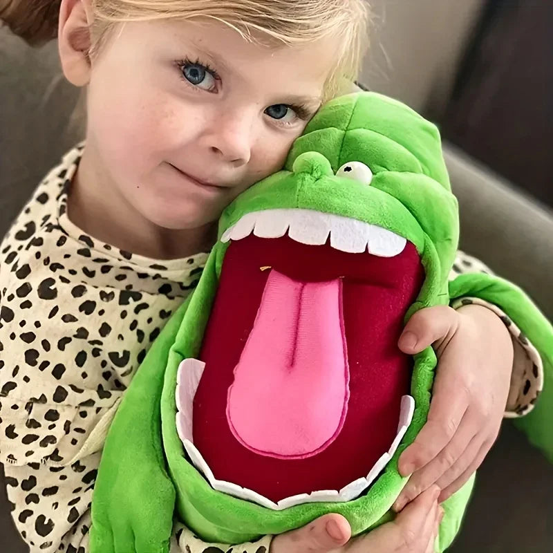 A young girl is smiling while holding a green ghost plush toy.