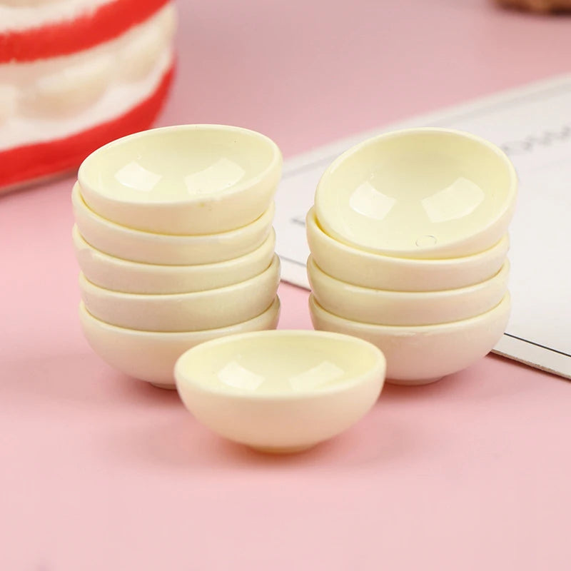 A set of ten small, white ceramic rice bowls stacked and displayed on a pink surface.