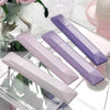 A collection of four purple and pink adhesive dot tape glue rollers displayed on a clear glass surface.