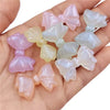 A collection of shimmering pink and iridescent mermaid-themed bowknot beads for jewelry making displayed in a hand.