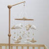 Handmade felt baby mobile featuring clouds and a moon suspended from a wooden bar.