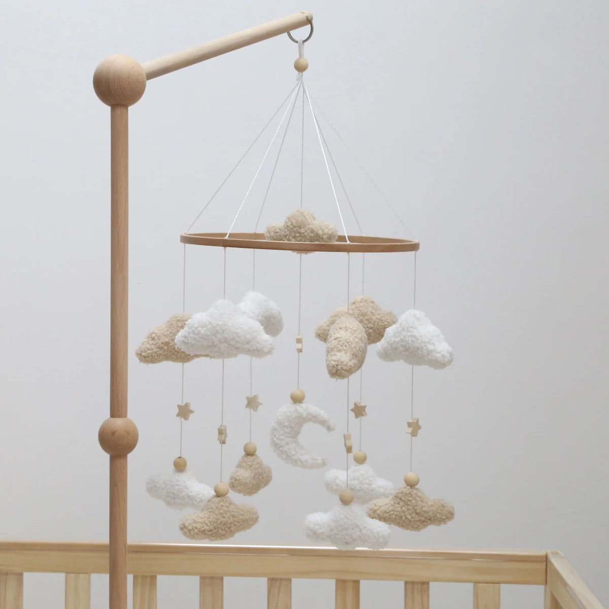 Handmade felt baby mobile featuring clouds and a moon suspended from a wooden bar.