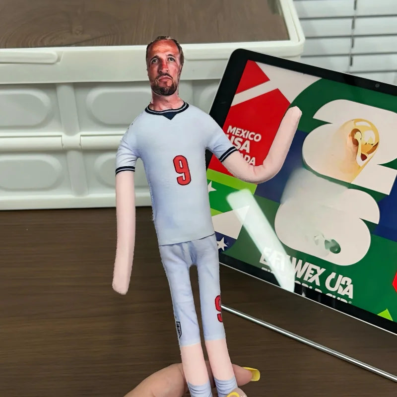 A realistic stuffed doll of Erling Haaland wearing a light blue football jersey and matching pants, displayed next to a graph