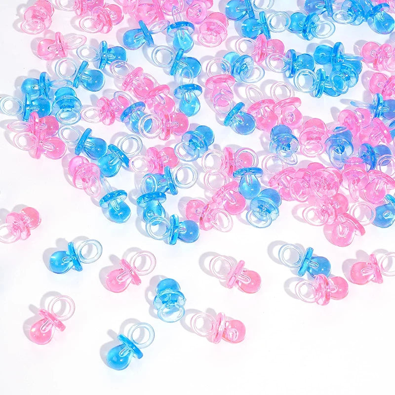 A large pile of mini acrylic pacifier party favors in various shades of pink and blue.