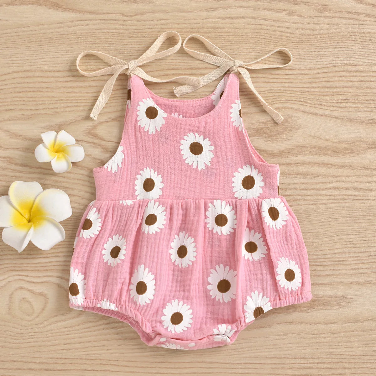 Pink cotton romper for a baby girl with white daisy floral print and adjustable ties