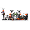 A miniature haunted house set featuring a graveyard, picket fence, spooky decorations like pumpkins and bats, and a ghostly f
