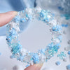 A circular wreath made of blue and white camellia resin flowers and pearl accents for DIY crafts.