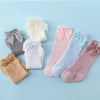 A collection of baby girl lace knee socks with bows in various pastel colors including white, pink, blue, and gray.