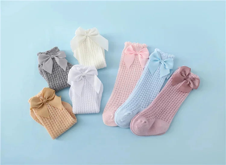 A collection of baby girl lace knee socks with bows in various pastel colors including white, pink, blue, and gray.