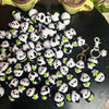 A collection of black and white crochet kitten keyrings with panda charms arranged on a dark surface.