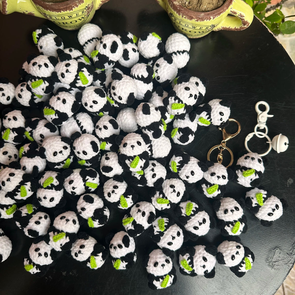 A collection of black and white crochet kitten keyrings with panda charms arranged on a dark surface.