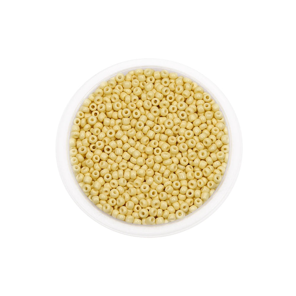 A clear plastic container filled with small, round, light yellow glass seed beads for jewelry making.