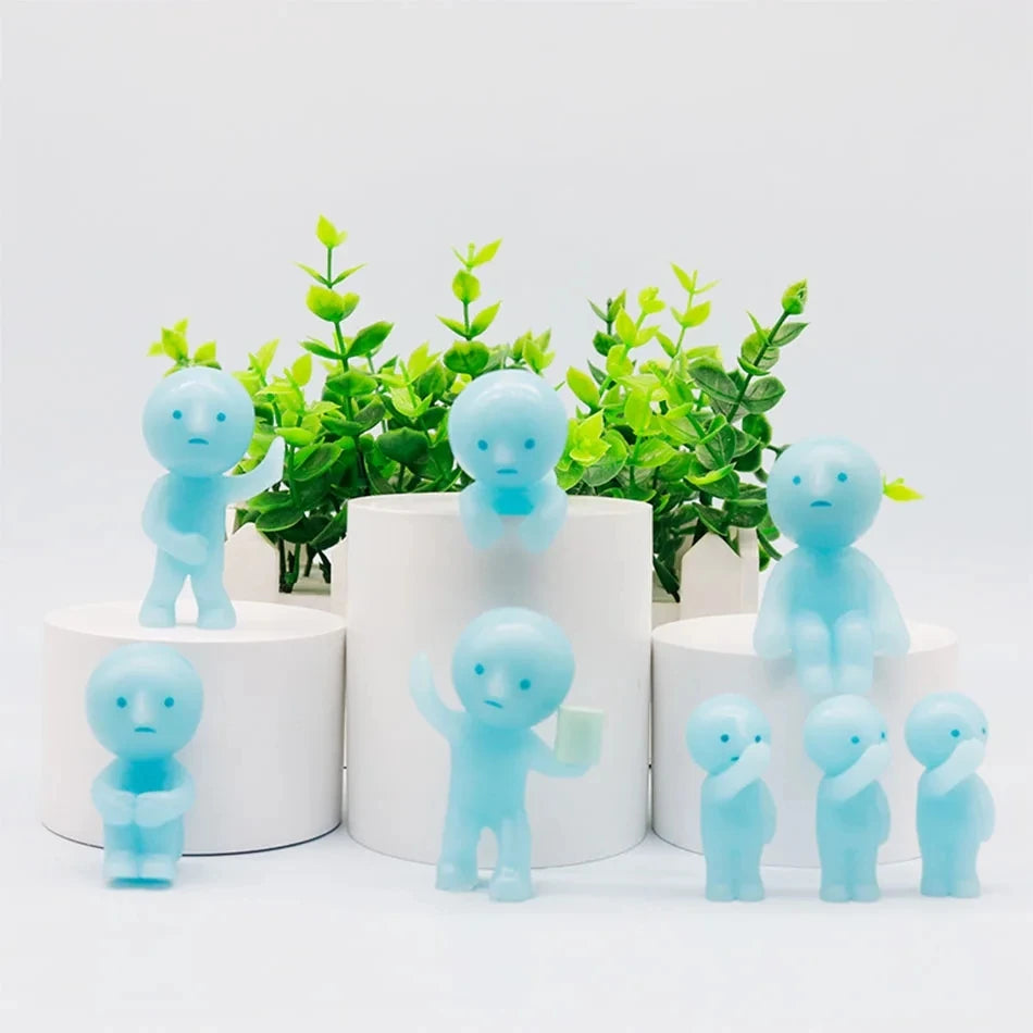 A collection of light blue glow-in-the-dark mini fitness figurines displayed on white circular stands with green foliage in t