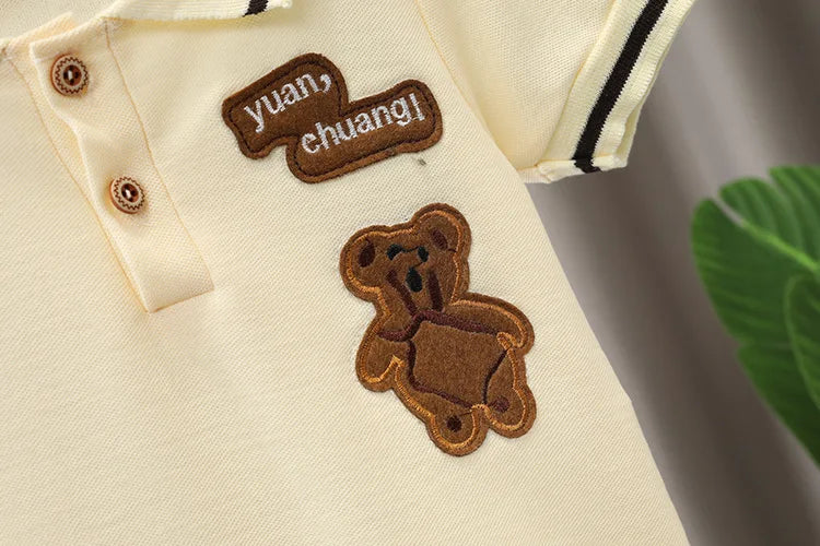 A beige cotton shirt features a brown embroidered text 'yuan chuang!' and a small brown bear patch on the chest.