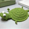 Handmade crochet lizard coaster in green with white eyes and a small white bump