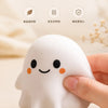 A white, squishy ghost-shaped stress ball is being held by a hand, emphasizing food-grade safety and fragrance-free features.