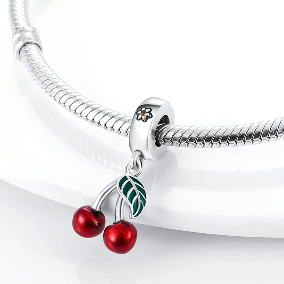 A silver fruit charm bead set featuring cherries and a leaf, attached to a sterling silver bracelet chain.