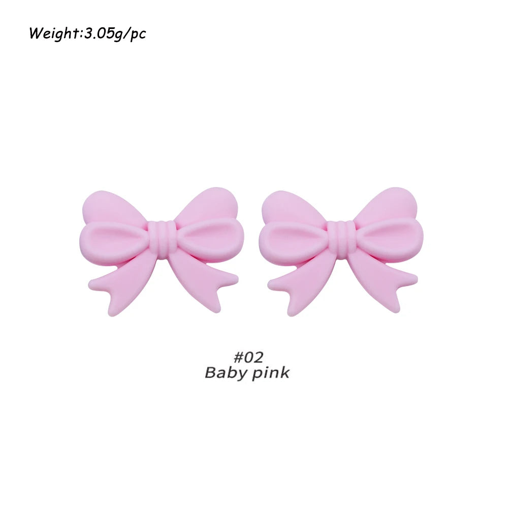 Two pink silicone bow tie beads used for jewelry making and craft projects