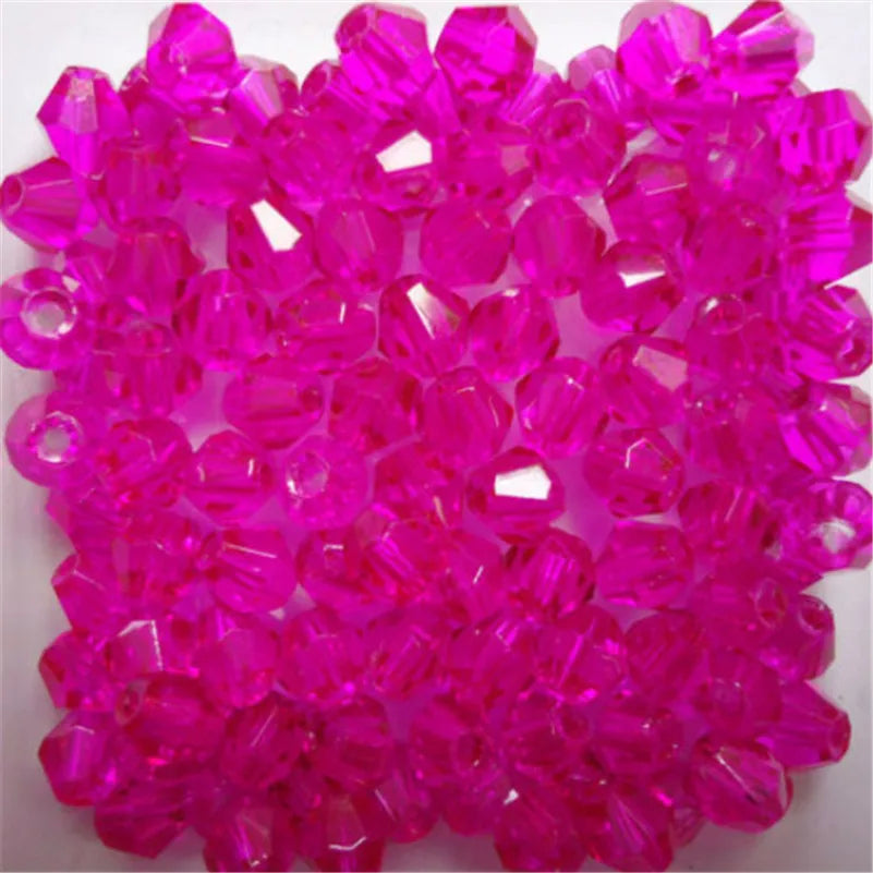 A pile of faceted pink glass bicone beads for jewelry making.