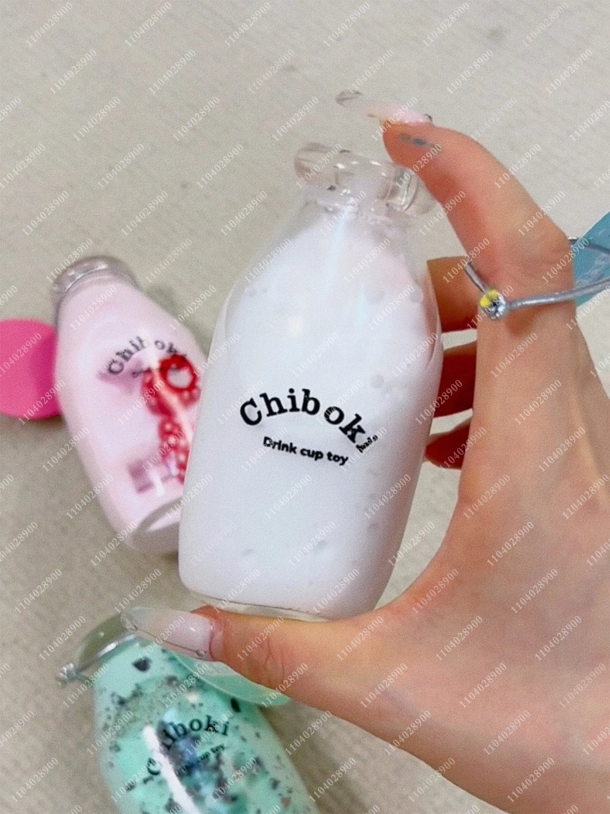 A hand is squeezing a white liquid in a glass bottle, demonstrating squishy milk bottle stress balls.