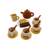 A silicone pretend play tea set featuring a brown teapot, cup, and saucer with a waffle food item.