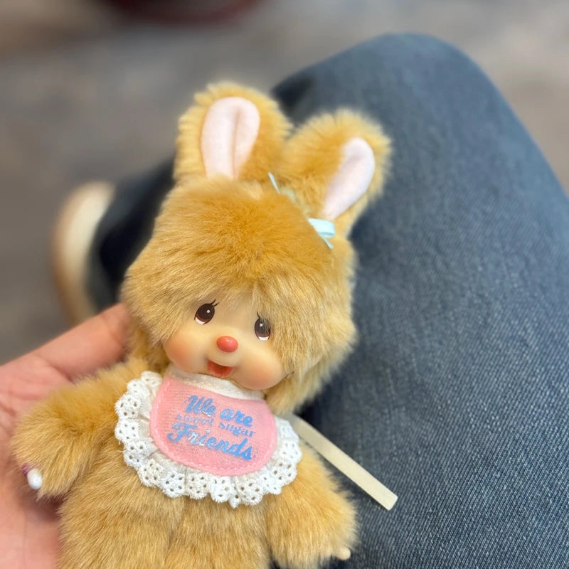 A fluffy orange rabbit plush toy with pink ears and a white lace collar resting on a person's hand.
