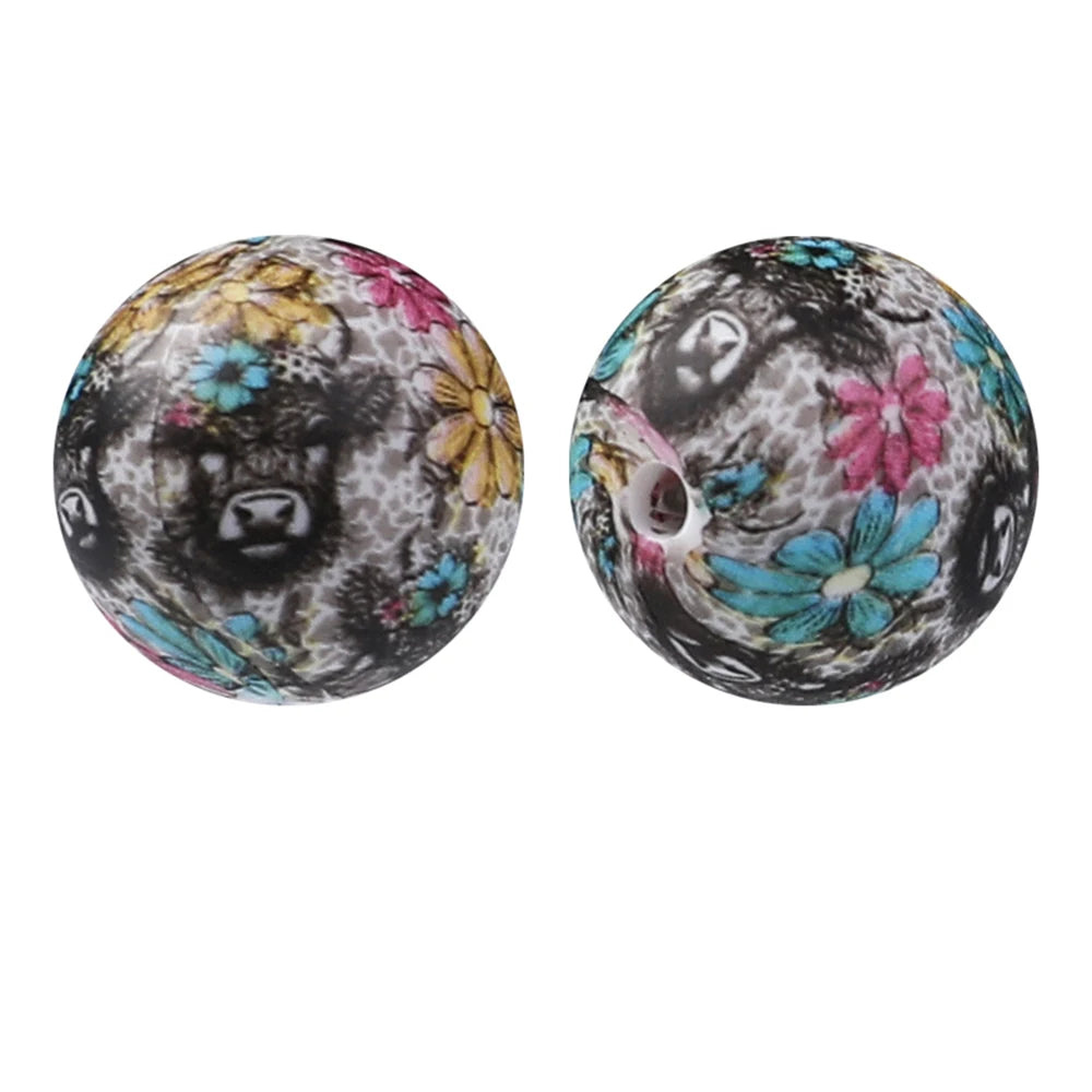 A pair of round silicone beads featuring floral and animal patterns in black, white, yellow, pink, and blue tones.