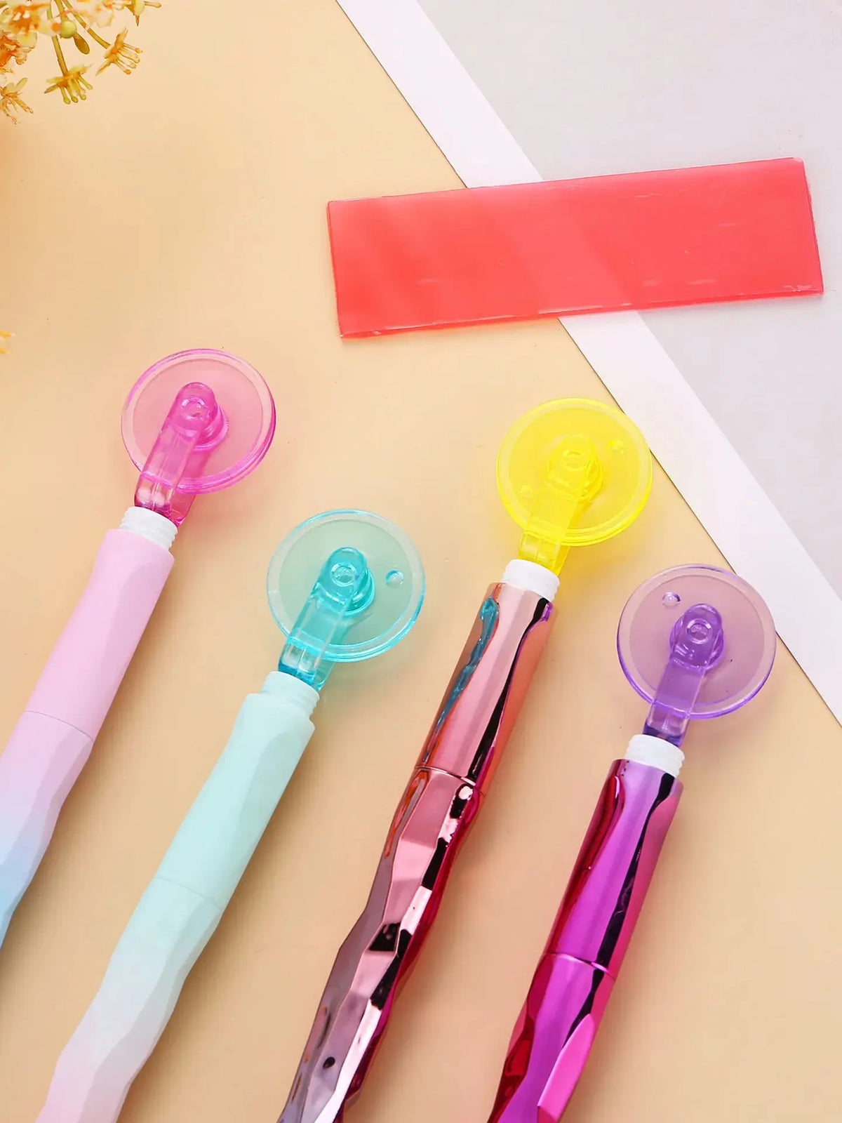 A collection of diamond painting pens in various colors, including pink, mint green, and purple, laid out on a light backgrou
