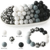 A collection of soft food-grade silicone beads in various shades of white, gray, and black arranged on a white plate.