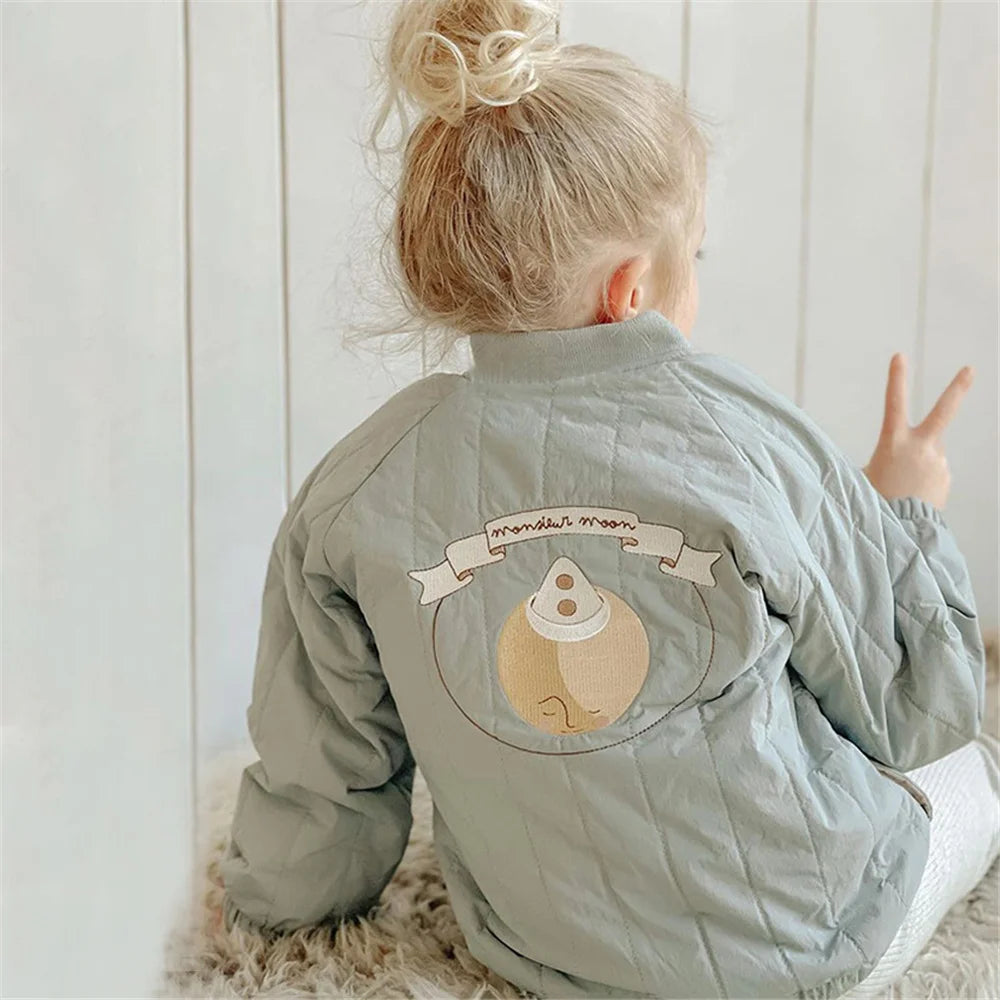 A young child is shown from the back wearing a light green padded jacket with a moon design print.