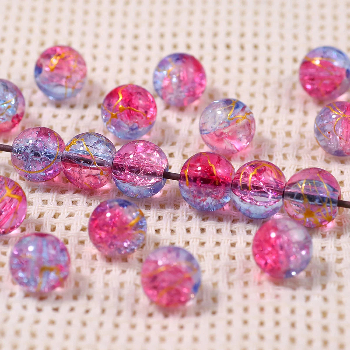 A string of iridescent pink and blue gradient crystal glass beads with a golden crackle finish