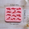 Pink silicone mold with various dinosaur shapes for baking and craft projects